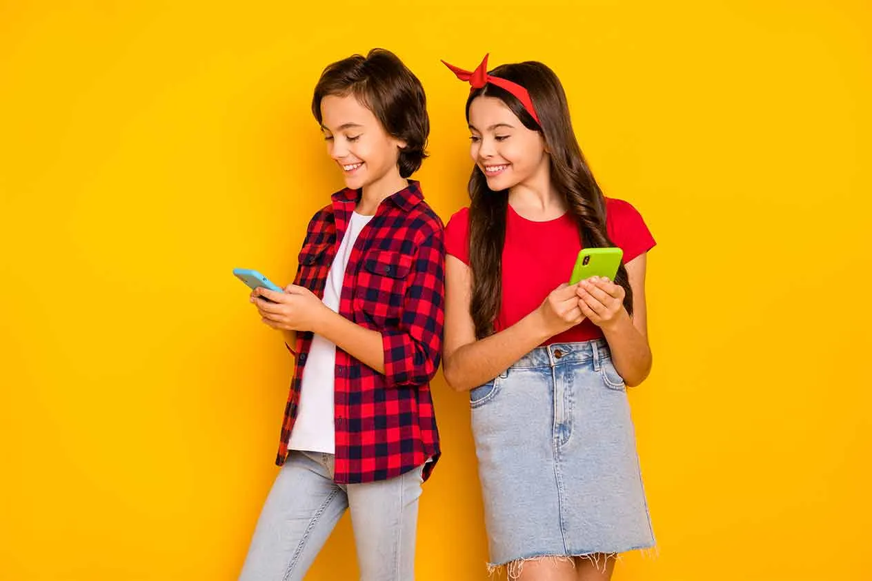 Dwoje nastolatków wpatruje się w ekrany telefonów